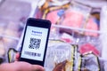 Selective focus to QR code tag on smartphone with blurry frozen food at supermarket