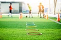 Selective focus to ring ladder marker and cone are soccer training equipment on green artificial turf with blurry kid players Royalty Free Stock Photo