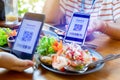 Selective focus to smartphone in hand to scan QR code on tag with blurry spicy Thai food