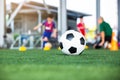 Selective focus to soccer ball on green artificial turf with blurry soccer team is training Royalty Free Stock Photo