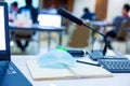Selective focus to wireless microphones and mask with blurry pencil on notebook in a meeting room
