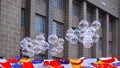 Transparent balloons floating above various hanging clothes decorations against brick stone building background
