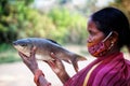 Selective focus on tribal women of women self help group SHG holding fresh rohu carp fish in hand in nice blur background