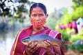 Selective focus on tribal women of women self help group SHG holding fresh rohu carp fish in hand in nice blur background