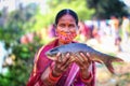 Selective focus on tribal women of women self help group SHG holding fresh rohu carp fish in hand in nice blur background