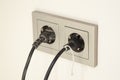 selective focus of two black plugs are plugged into a double electrical outlet with a frame