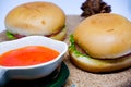 Selective focus of two hamburgers on wooden tray with chili sauce. Royalty Free Stock Photo