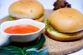 Selective focus of two hamburgers on wooden tray with chili sauce. Royalty Free Stock Photo
