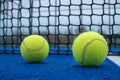 Selective focus. Two paddle tennis balls on a blue court with the net out of focus in the background Royalty Free Stock Photo