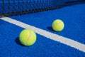 Selective focus two paddle tennis balls on a blue paddle tennis court with a net in the background Royalty Free Stock Photo