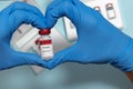 Selective focus of a vial of Covid19 vaccine held by latex gloves creating a heart as a hope to end the pandemic