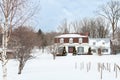 French-style patrimonial white double house with shingles and metal roof in a snowy land