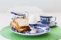 Selective focus view of boiled egg in pretty painted ceramic holder and slices of bread in plate