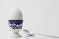 Selective focus view of boiled egg in pretty painted ceramic holder and spoon