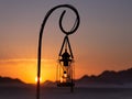 Selective focus view of lantern on hook seen during a colourful sunset in a desert area