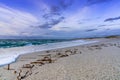 Selective focus view of white sand beach with waves rolling in under a colorful sunset sky Royalty Free Stock Photo