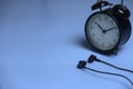 Selective focus of vintage alarm clock and earphone with copy space on a blue background