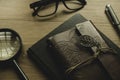 Selective focus of vintage notebook, magnifying glass,pen and glasses on wooden background