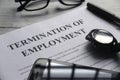 Selective focus of watch,mobile phone,pen,glasses and Termination of Employment letter on a white wooden background