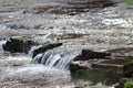 Selective focus of a water flowing over a stone cascade, with a sparkling surface in the background Royalty Free Stock Photo