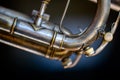 Selective focus on a water key of an aged wind instrument trumpet.