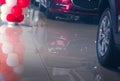 Selective focus on Wheel and tires of new red car parked in modern showroom with reflection on tile floor and balloons. Car Royalty Free Stock Photo