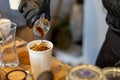 selective focus white paper cups A coffee shop worker wearing black rubber gloves is pouring a shot of black coffee into a paper