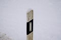 Selective focus of a white reflector post covered with snow during winter Royalty Free Stock Photo
