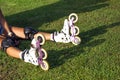 Selective focus on white roller skate with seated Eurasian butterfly small tortoiseshell. Cropped photo of girl sitting on green Royalty Free Stock Photo