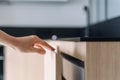 Selective focus on woman hand opening door on wooden cabinet under countertop Royalty Free Stock Photo