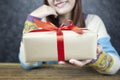 Selective focus of Woman hands holding gift box with red ribbon Royalty Free Stock Photo