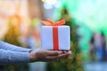 Selective focus of Woman hands holding white gift box with orange ribbon on bokeh abstract background for Christmas and New Royalty Free Stock Photo