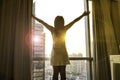 woman looking at dawn city scenery and stretch the muscles at window. Health concept