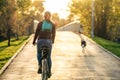 Woman riding a bike next to a dog that is running in a park during sunset Royalty Free Stock Photo