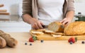 Selective focus woman or wife hand holding knife, cutting bread in cozy home kitchen in morning, preparing healthy meal for Royalty Free Stock Photo