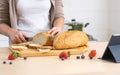 Selective focus woman or wife hand holding knife, cutting bread in cozy home kitchen in morning, preparing healthy meal for Royalty Free Stock Photo