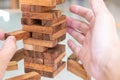 Selective focus at wood brick. Business people using hand to pull out wood brick with caution. taking risk and make decision to