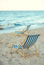 selective focus of wooden beach chairs on sandy beach with sea Royalty Free Stock Photo