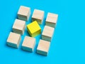 Selective focus wooden cubes with yellow color at the center isolated on blue background.