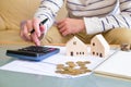 Selective focus at the wooden house with Asian men calculating his money for buy a new house or plan for home loan mortgage. Royalty Free Stock Photo