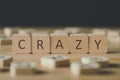 Focus of word crazy made of cubes surrounded by blocks with letters isolated on black