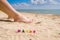 Selective focus on the word Happy on the background of female feet and the sea. Royalty Free Stock Photo