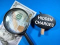 Selective focus.Word HIDDEN CHARGES on black board with magnifying glass and dollar banknote on blue background.Business concept. Royalty Free Stock Photo