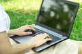 Selective focus working on laptop outdoors.Woman sitting on grass at park,relaxing while under a tree.Nature essential wellbeing