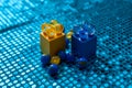 Selective focus of yellow and blue marbles on cubes on blue sequin fabric Royalty Free Stock Photo