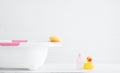 Selective focus on yellow sponge on white and pink baby bathtub near pink shampoo or shower gel bottle and yellow rubber duck toy Royalty Free Stock Photo