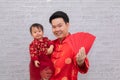 Selective focus young Asian Father hold hug his daughter with love and care and show many red envelop anpao to camera with happy 