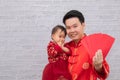 Selective focus young Asian Father hold hug his daughter with love and care and show many red envelop anpao to camera with happy 