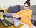 Selective focus young beautiful asian woman wore glasses and orange knitwear sitting by gray sofa