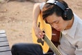 Selective focus of young relaxed man is playing acoustic guitar in outdoor.